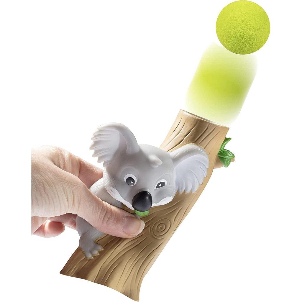 The koala popper is being shown firing a ball into the air by someone squeezing the koala and tree.