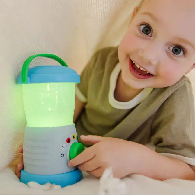 Image of a little boy playing with the Sights & Sounds Lantern. Currently the lantern is green.