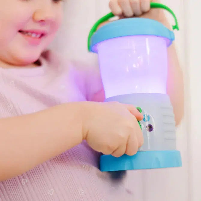 Image of a little girl playing with the Sights & Sounds Lantern. Currently the lantern is purple.
