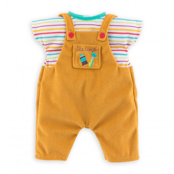 The outfit consists of a white t-shirt with horizontal rainbow stripes attached to a pair of light brown overalls. The overalls have a front pocket with art supplies on it and the brand name Corolle