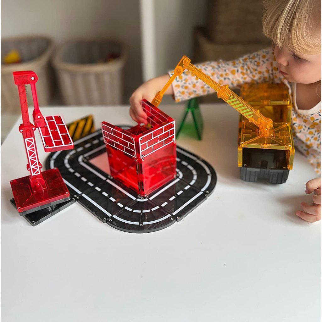 the magnetic builder crane is helping a child build a magna tile house, and a magna tile road