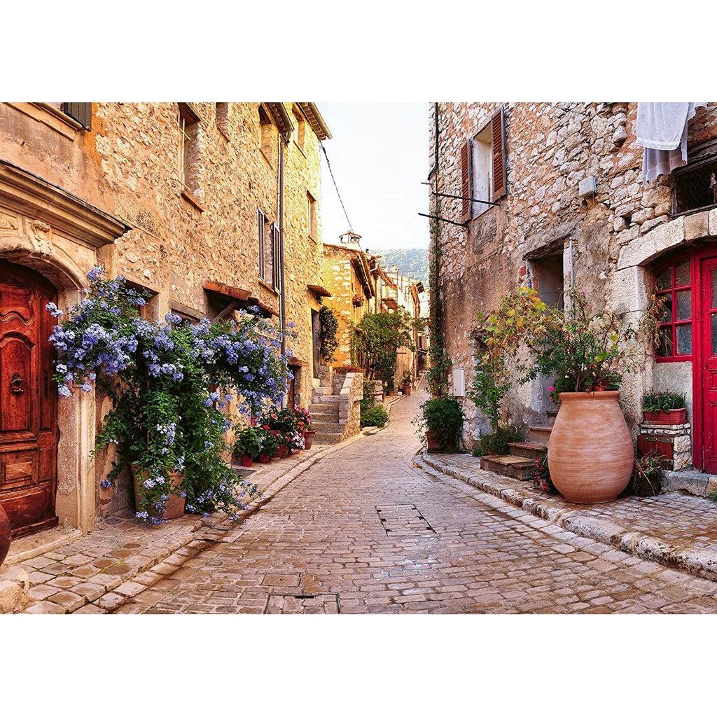 Puzzle image | View down a narrow cobblestone street with tall stone building on either side | Doorways and windows line the buildings, and large clay pots with flowers line the whole street.