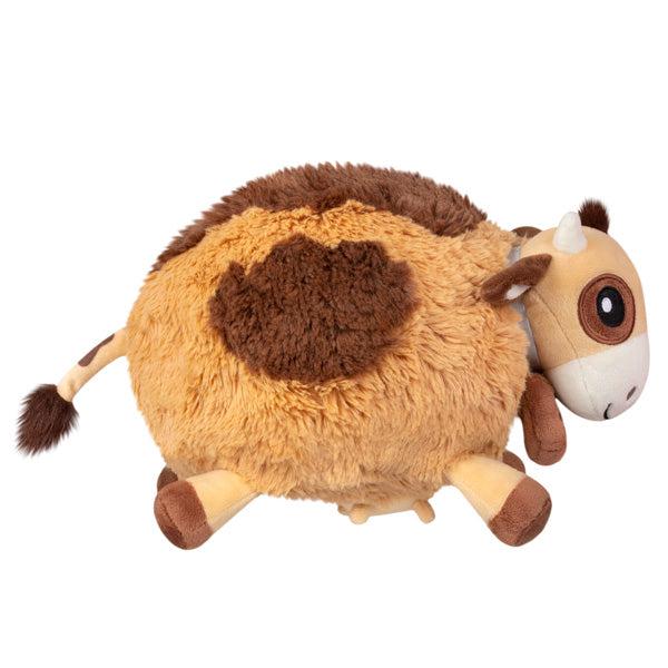 Side view of the plush. Shows that the cow has a sign hanging around its neck and you can see an udder hanging down from its stomach.