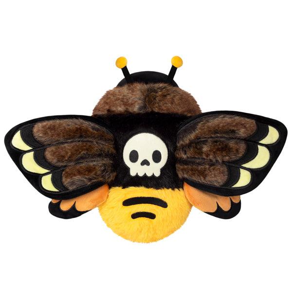 Top view of the plush. On its back is an embroidered white skull. Its butt is bright yellow.