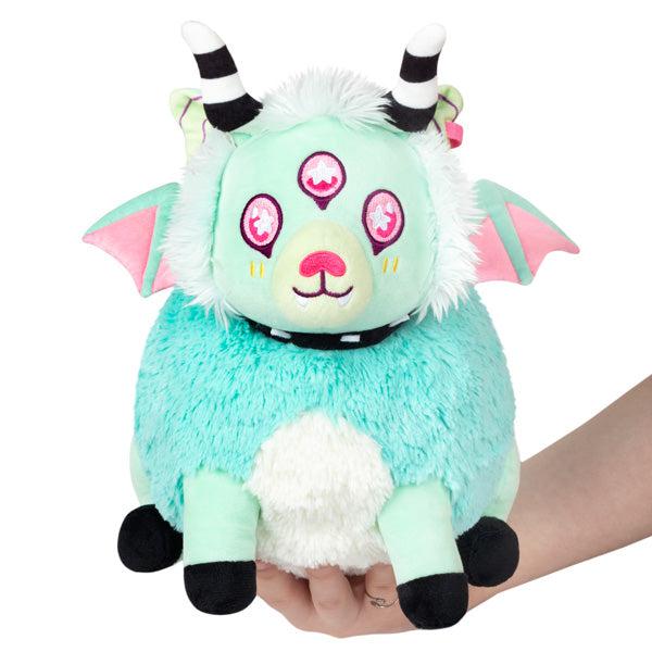 Image of the Mini Pastel Demon squishable. It is a teal, mint, and pink creature with spooky wings, antlers, and three eyes.