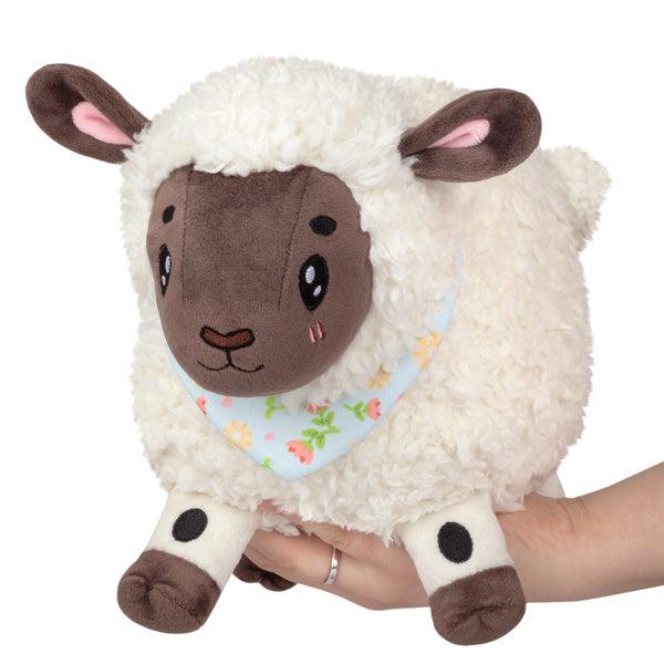 Image of the Mini Spring Lamb squishable. It is a soft and fluffy white lamb with black skin. It is wearing a spring flower necktie.