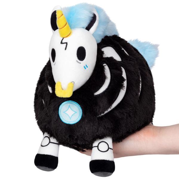 Image of the Mini Undead Unicorn squishable. It is a black and white unicorn with a yellow horn, yellow nose ring, and electric blue mane and tail.