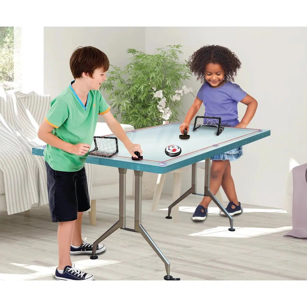 two children are playing air hockey on a table! the rope and suction cups help the puck stay in the table!