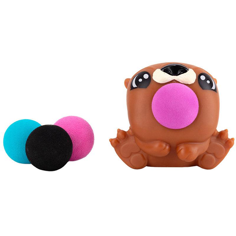 Up close shot of the Otter PeeWee Popper and the 4 foam balls that it comes with. The otter is a reddish brown color and the balls are different colors (purple, pink, blue, and black.)