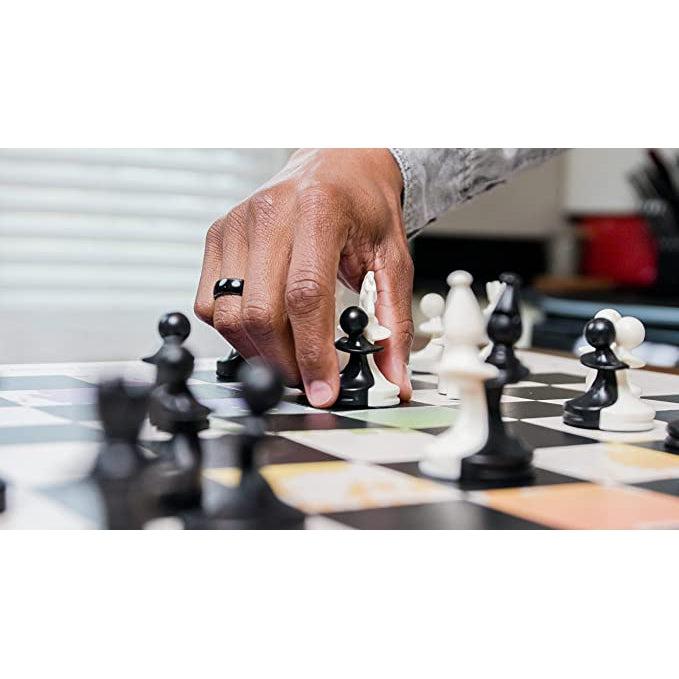 Image shows chess pieces mid-game play. A hand grasps a black pawn and white night between two fingers, pushing them together so they fit and sit together on the same space. | Other chess pieces in the image can also be seen merging and sharing game spaces.