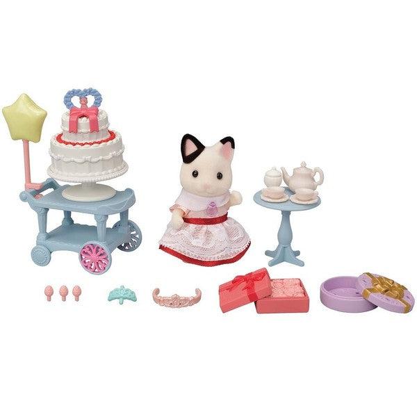 Image of all the included pieces outside of the packaging. The set includes a tuxedo cat girl wearing a red and white party dress, a cake cart with a two-tiered cake, a white tea set with tea table, two gift boxes, a balloon, and two tiaras.