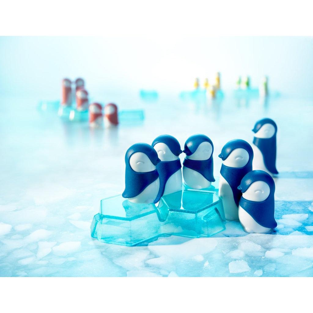 Close up of penguin and ice block pieces. | Group of blue penguin pieces sit on and around an ice block piece. | Other penguin/ice block groups are blurred but visible in distance.