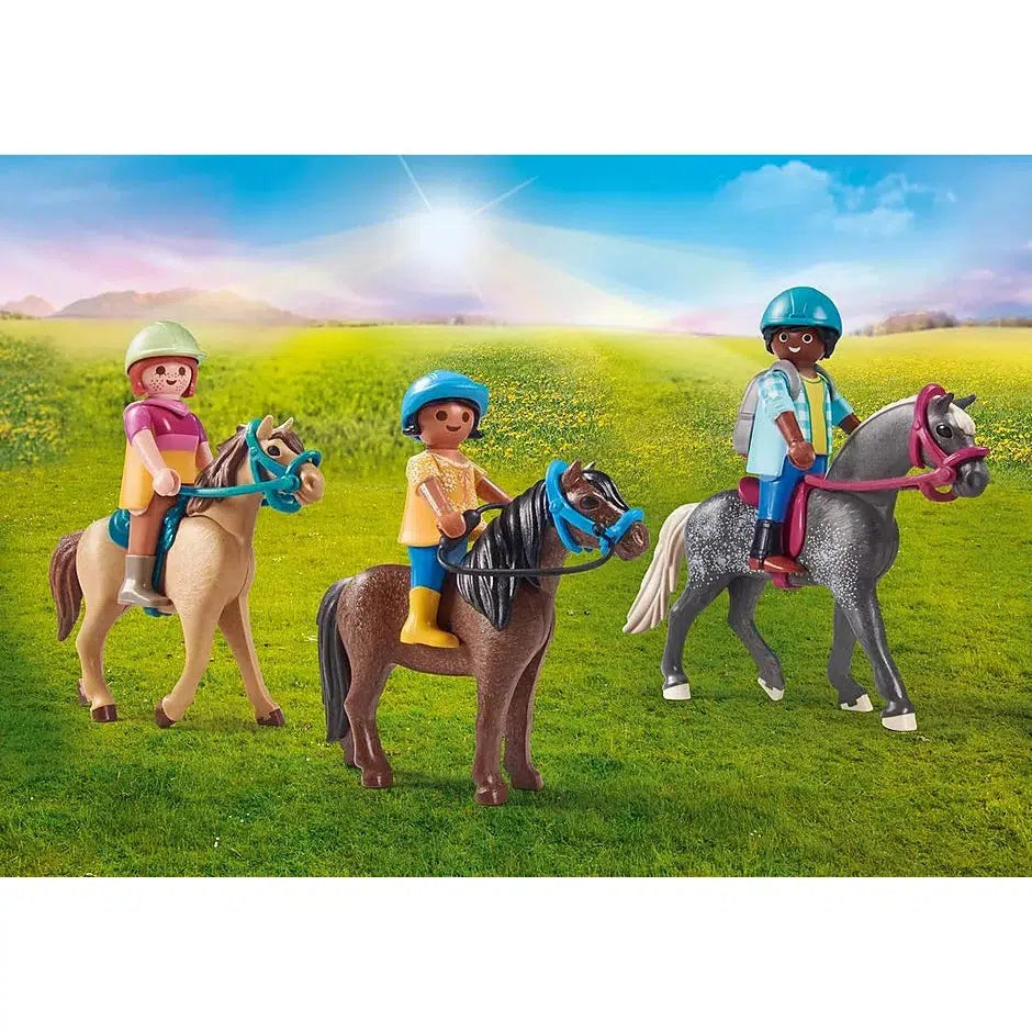The three playmobil figures, 2 adult figures, and one child figure, ride the three horses, one gray with white spotted legs and a white mane, one tan with brown mane, and one brown with black mane