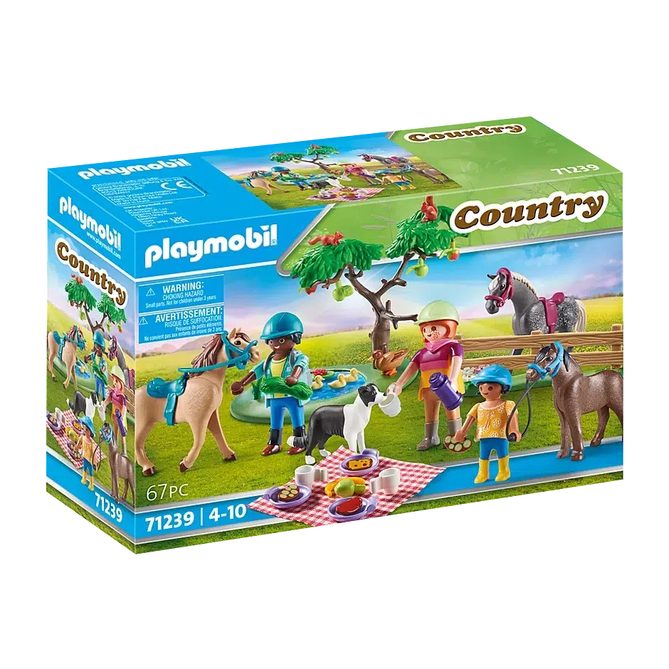 The front of the box shows the 3 playmobil figures, 3 horse figures, and dog figure, at a picnic with a fence, a tree, and a pond