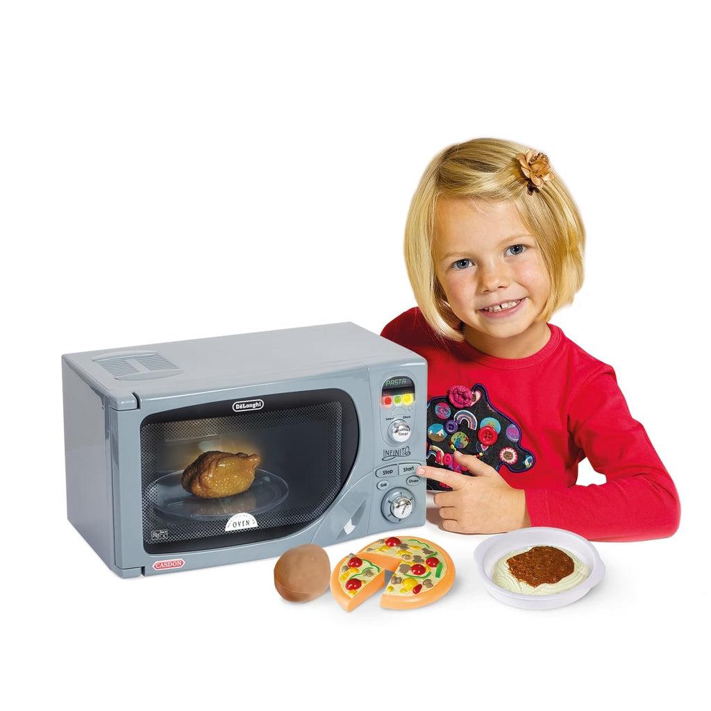 Scene of a little girl pointing to the microwave while it is cooking chicken.