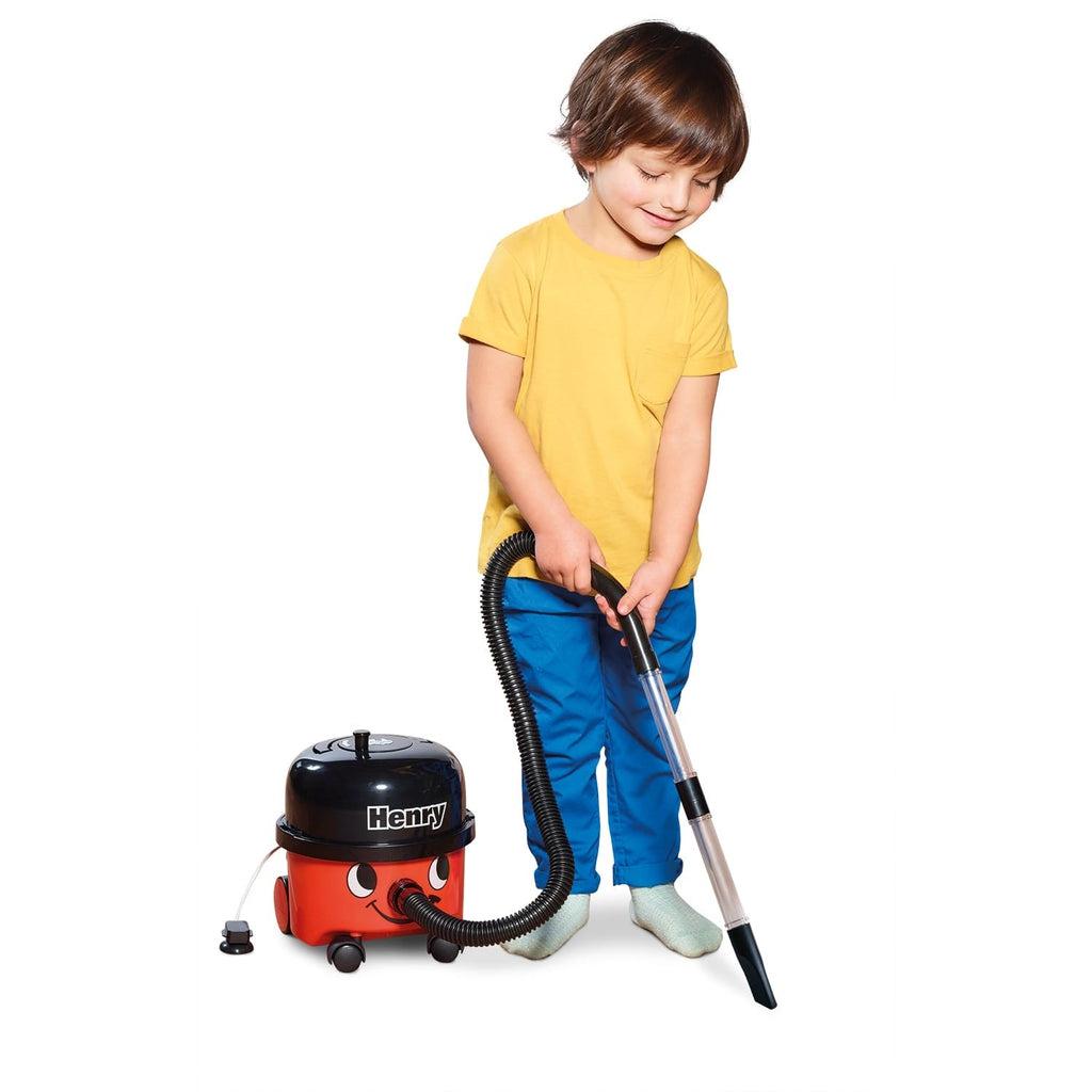 Scene of a little boy smiling while using the vacuum to clean up.
