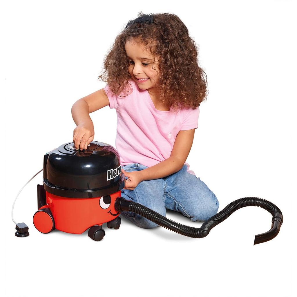 Scene of a smiling little girl opening the vacuum cleaner.