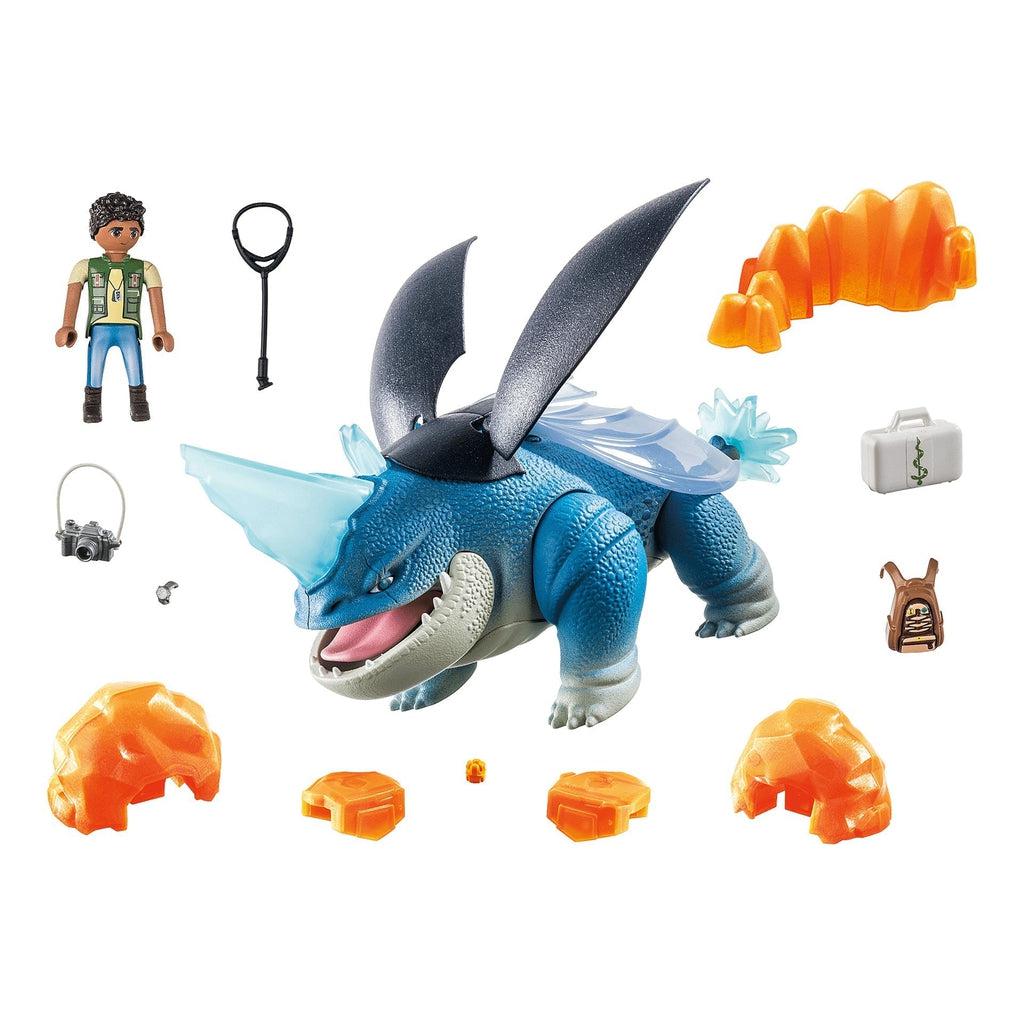Image of all the included pieces in the set outside of the packaging. It includes a chunky blue dragon with black and clear wings, a dragon rider, a camera, and a medical pack.