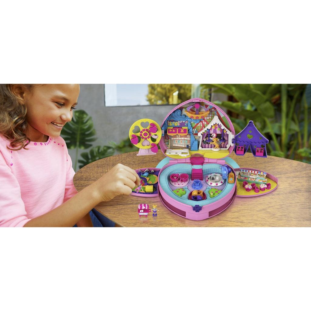 Young girl sits at a table playing with Polly Pocket Theme Park backpack.