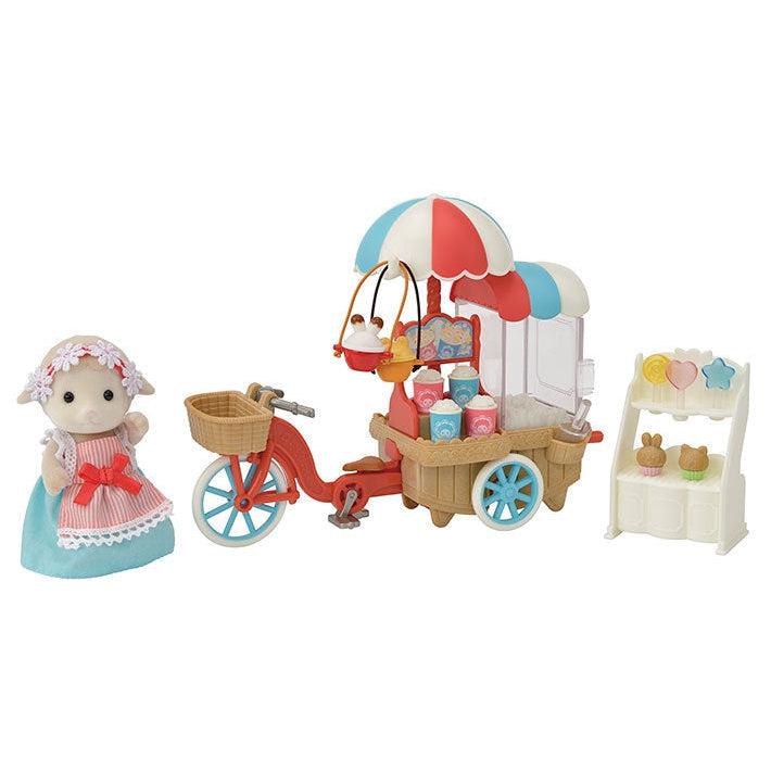 Image of the set outside of the packaging. It includes a sheep doll wearing a dress, a bicycle with attachable popcorn cart, and a muffin stand.