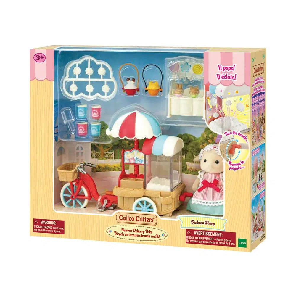 Image of the packaging for the Calico Critters Popcorn Delivery Trike. The front of the packaging is made from clear plastic so you can see all the included pieces inside.