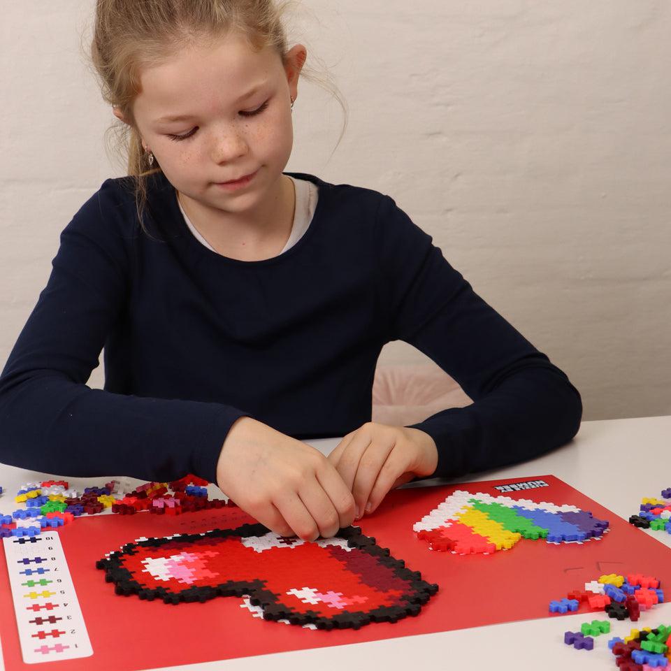 Young girl assembling Puzzle by Number using Plus Plus pieces and outline