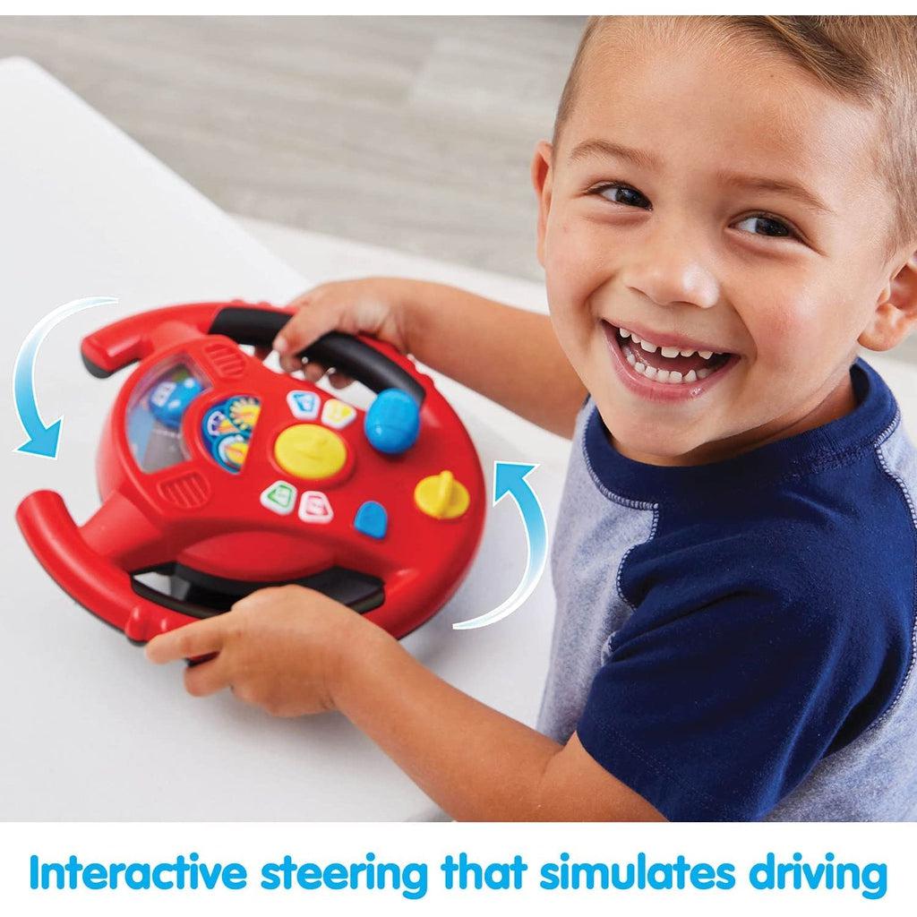 Scene of a little boy smiling and steering with his very own wheel.