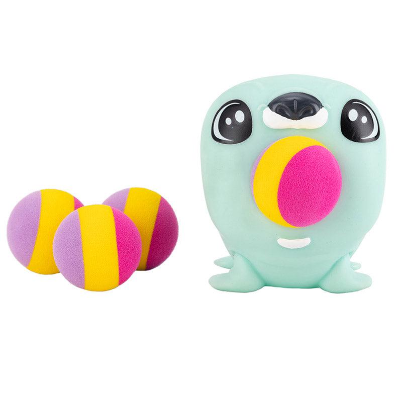Close up shot of the Seal PeeWee Popper and the 4 foam balls it comes with. The seal is a light blue color and the balls are multi-colored and striped (lavender, yellow, and pink).