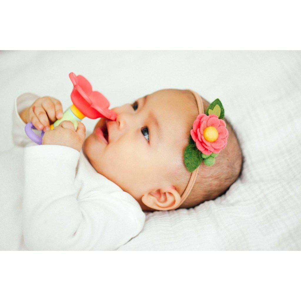 Scene of a baby holding the flower up to her nose as if smelling it.