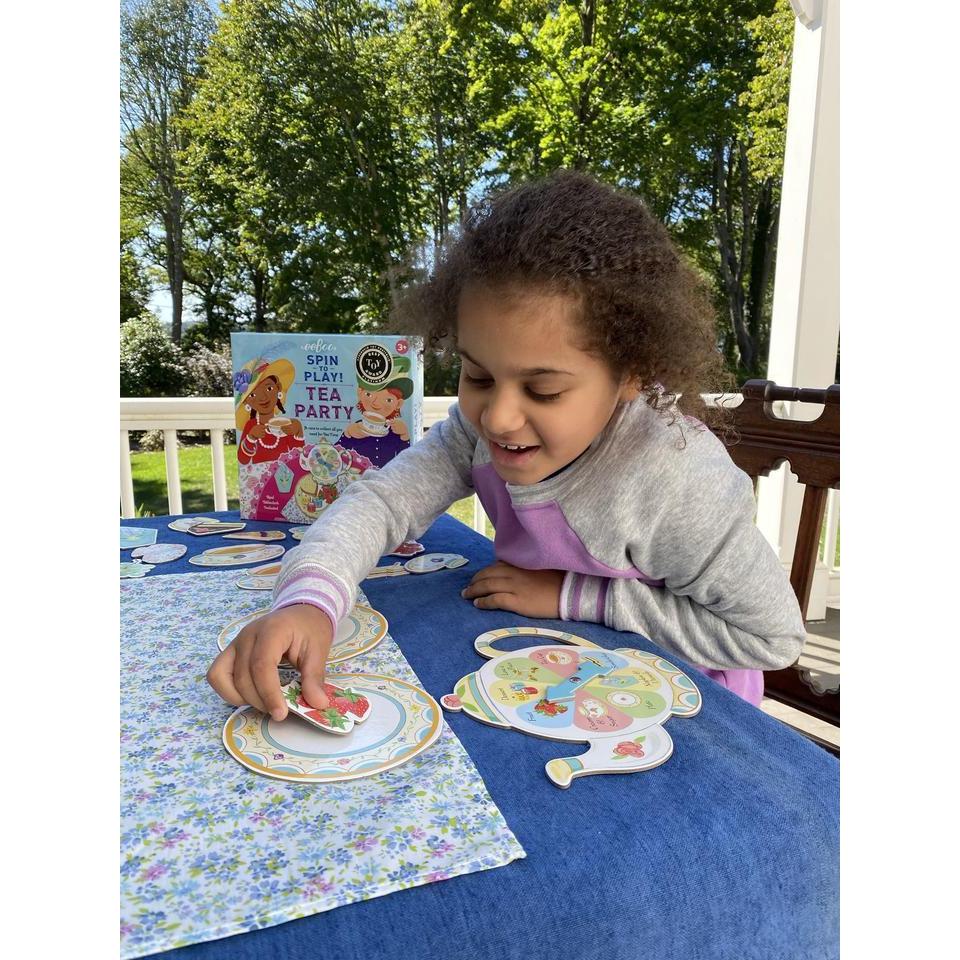 a child is playing with the spinner, she is grabbing a paper pastry for her plate