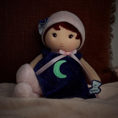 The doll is shown on a couch with the light dimmed so the moon on the front of the dress glows