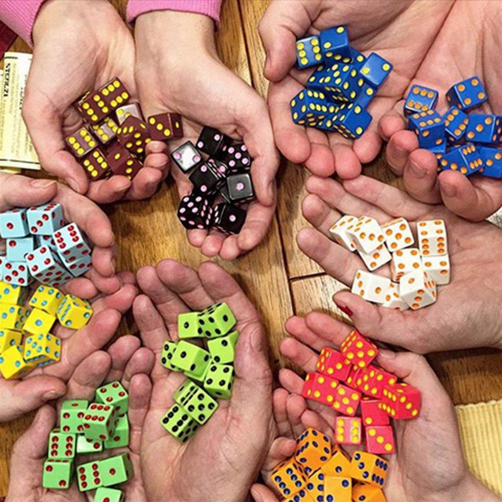 image shows a bunch of hands each holding a colored handful of dice, one hand has all white die, another all red, and another all green. 