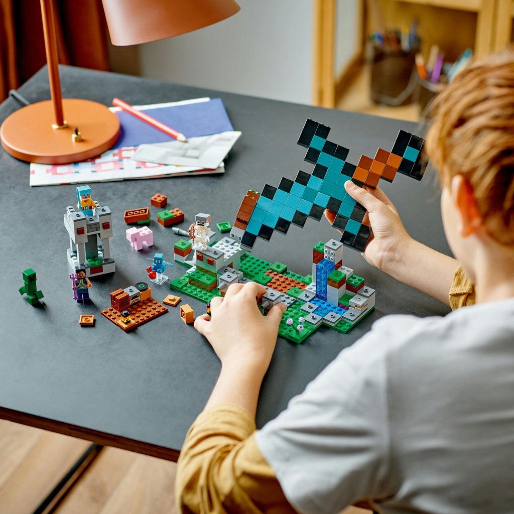 A kid is shown about to attach the sword portion of legos to the base and hill.