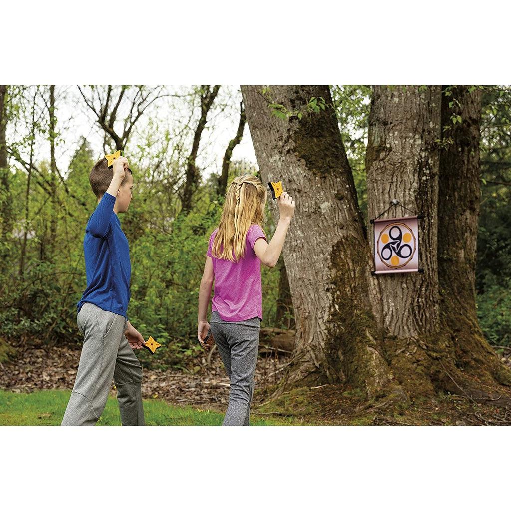 two children are shown outside preparing to throw the stars at the target which is hanging from a tree.