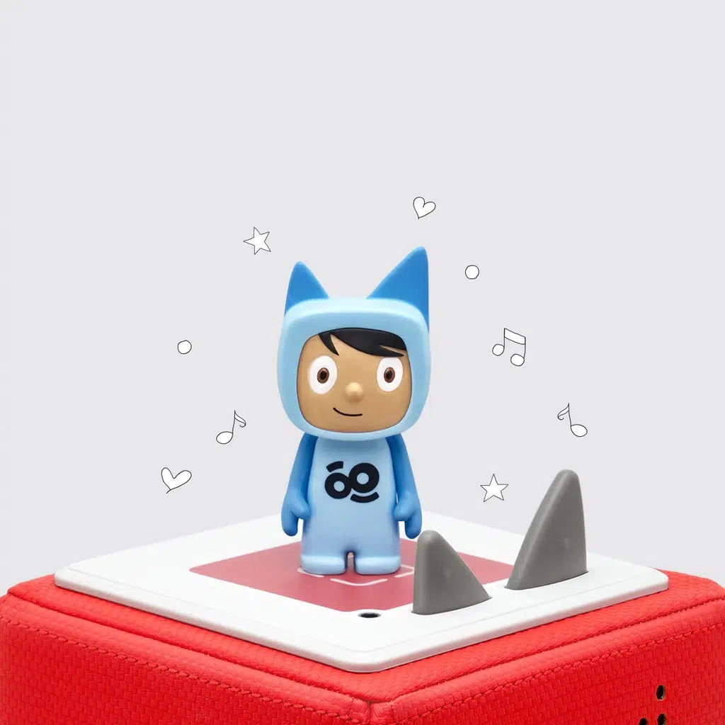 The figure is a boy in a blue jumpsuit with ears like the toniebox volume buttons, the front of the suit has the GoNoodle logo, an infinity sign with a line above the left half and below the right half. Figure shown on a red toniebox