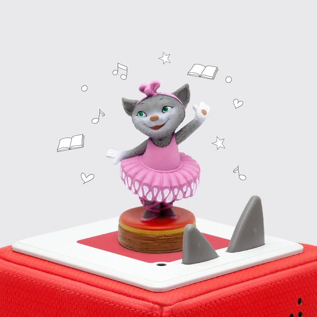 Mia Tonie, a grey cat with green eyes wearing a pink tutu, hair band, and ballet shoes, is on top of a red toniebox