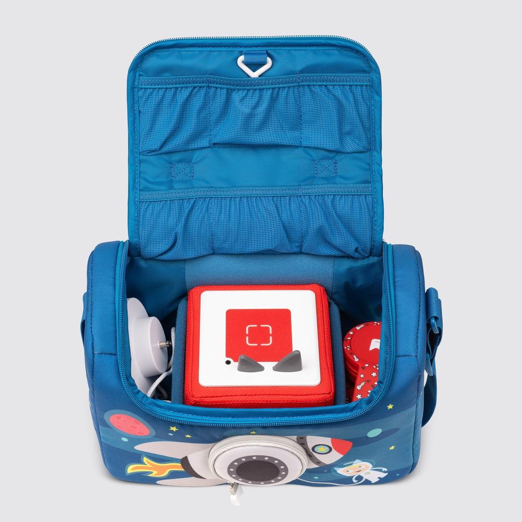bag is shown with the top zipped open, there are pockets on the inside of the top flap, inside the bag the toniebox is seen with a charger to the left of it and headphones to the right.