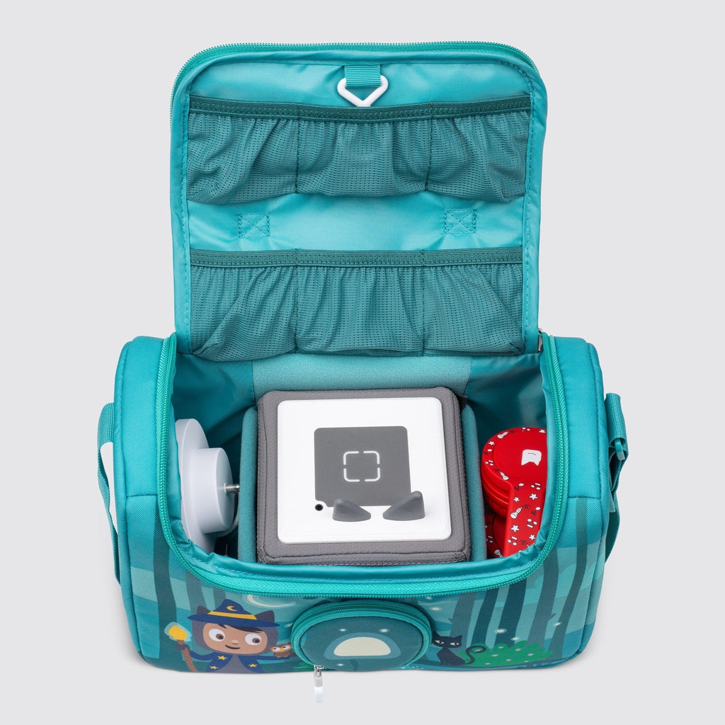 bag is shown with the top zipped open, there are pockets on the inside of the top flap, inside the bag the toniebox is seen with a charger to the left of it and headphones to the right.