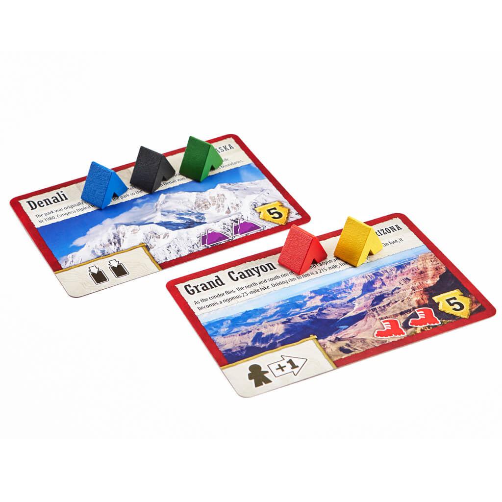 Example game cards | Cards provide name, image, and information about a national park as well as game play instructions associated with card. | Small wooden tents sit on each card.