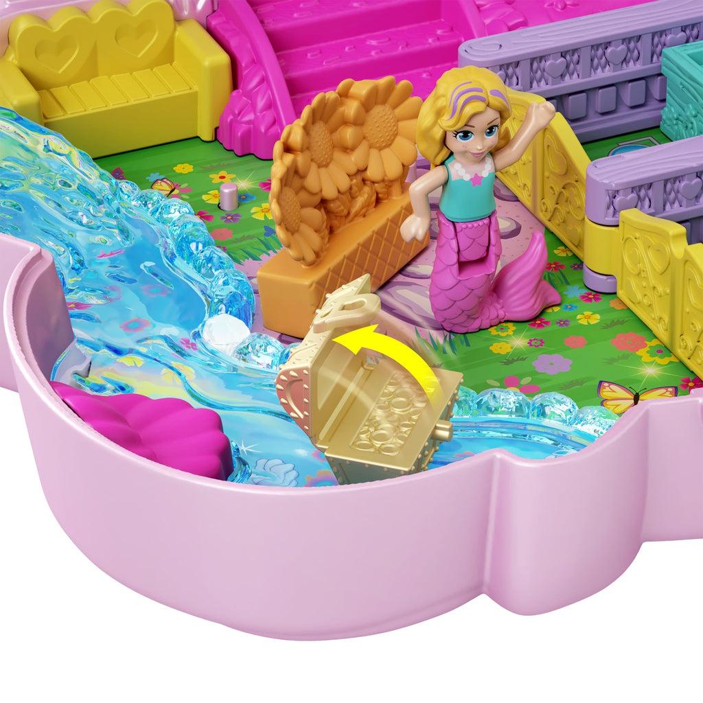 Close-up of bottom half compact | Mermaid figure sits by river with flower box nearby. Treasure chest accessory sits in river and a yellow arrow highlights the opening feature of the chest.