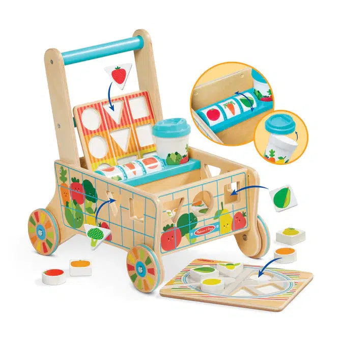 Image of the cart showing that the board can be stored in a special place of the cart, the fruit wheel can be spun, the lid can come off of the cup, and the fruits and vegetables can fit on the plate and through the holes in the side of the cart.