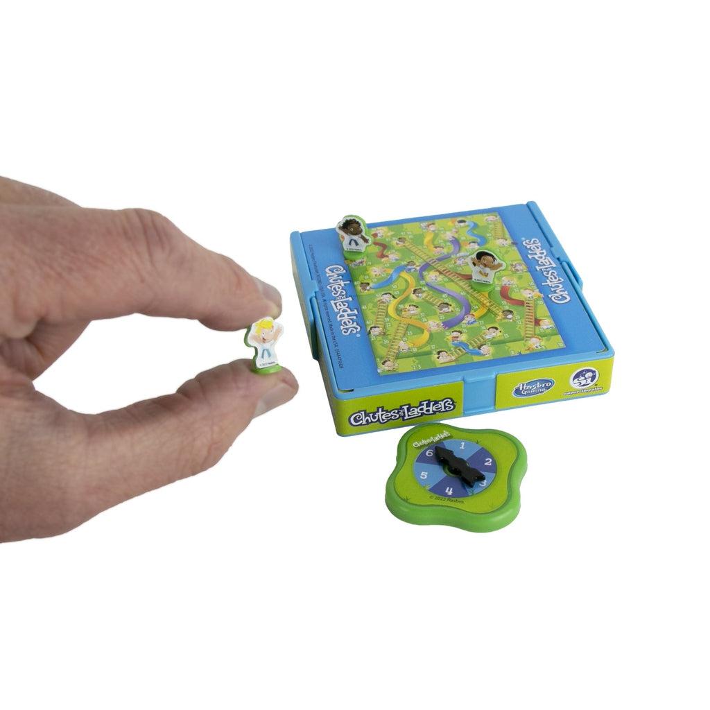 Shows a hand placing a game piece on the board for a size comparison. The board is smaller than a child's palm.